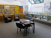 Raum im Reclam Museum mit Bücherregalen voller Reclam Büchern, zwei Sesseln und einem Tisch mit Stuhl